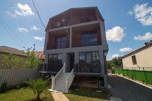 A two-story building with a balcony on the upper floor, a staircase leading to the entrance, and a fenced yard. - Prestige Guest House (Kutaisi)