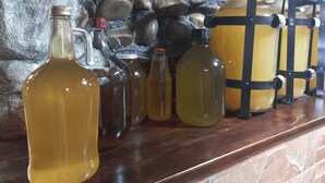 A variety of glass containers on a wooden shelf against a stone wall. - Prestige Guest House (Kutaisi)