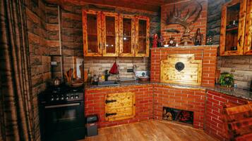 A rustic kitchen with wooden cabinets, a stove, and a brick backsplash.