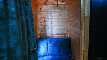 En stuga med träpanel i taket, en blå soffa och en dörr.
