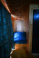 Een cabinteer met een houten plafond, een blauwe bank en een deur.