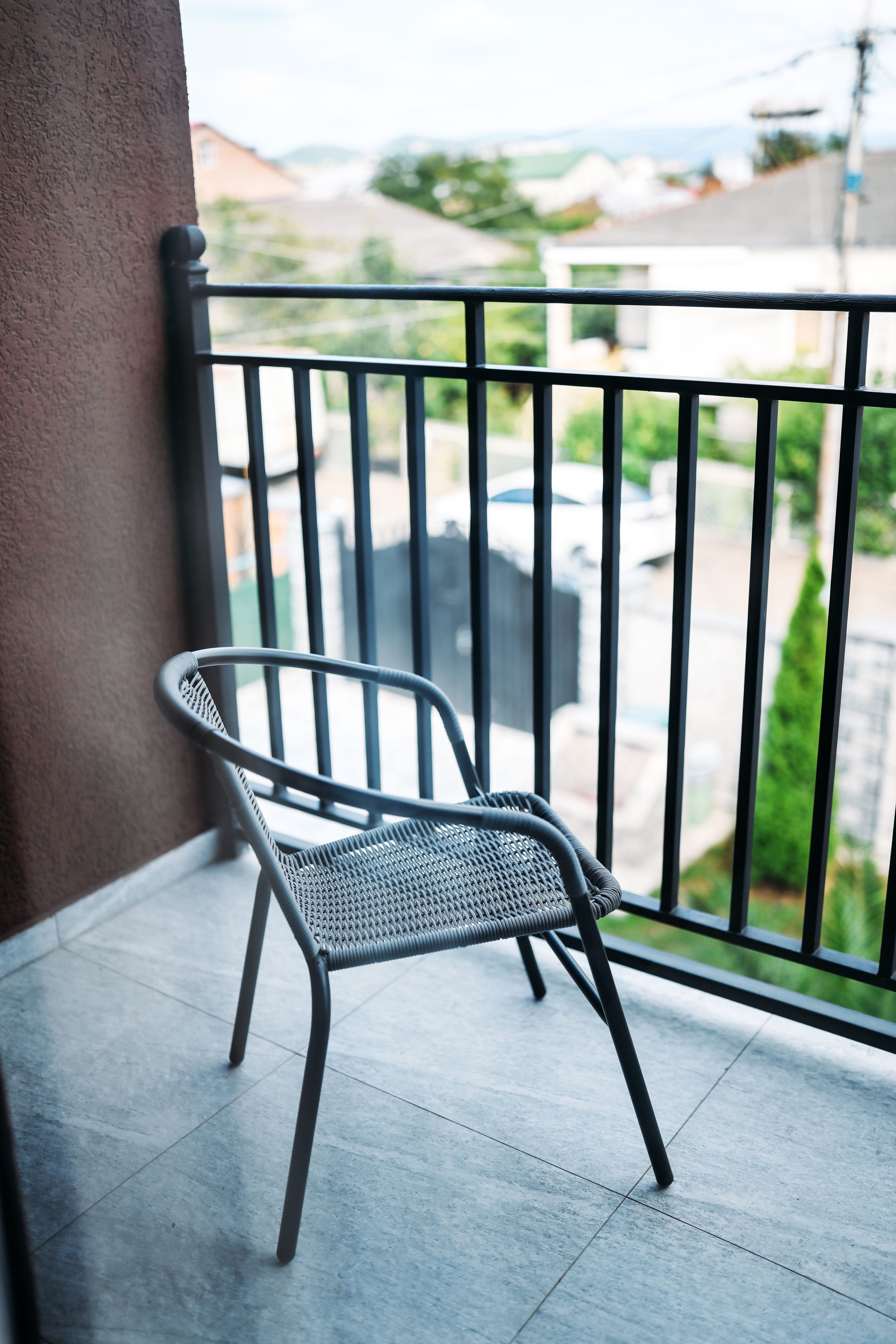 A chair on a balcony with a view of a residential street.