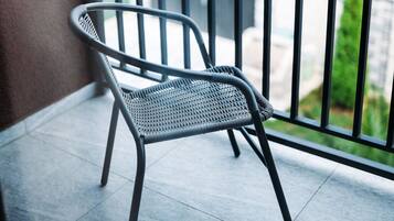 A chair on a balcony with a view of a residential street.