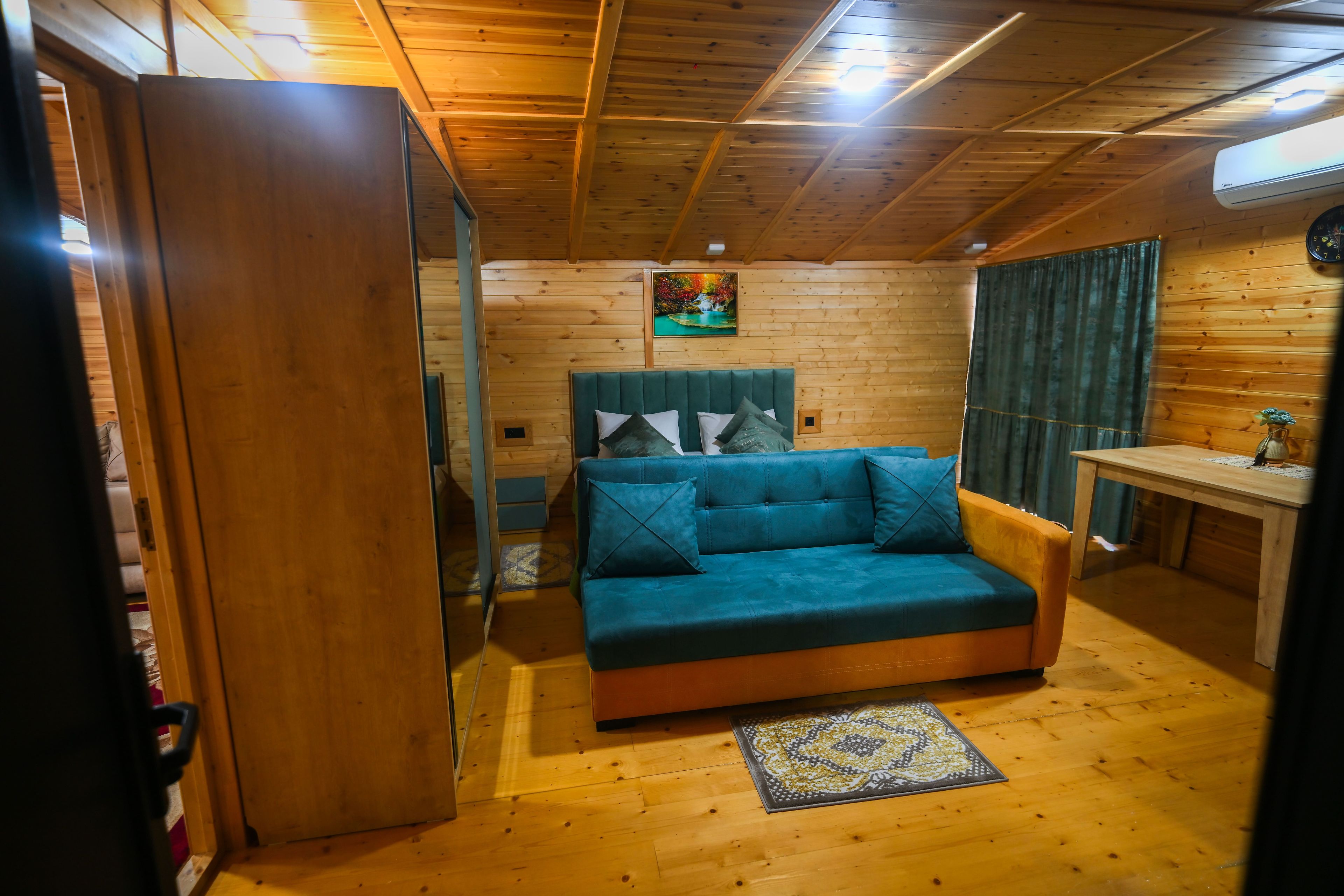 A cozy room with a bed, a small table, and a wooden ceiling.