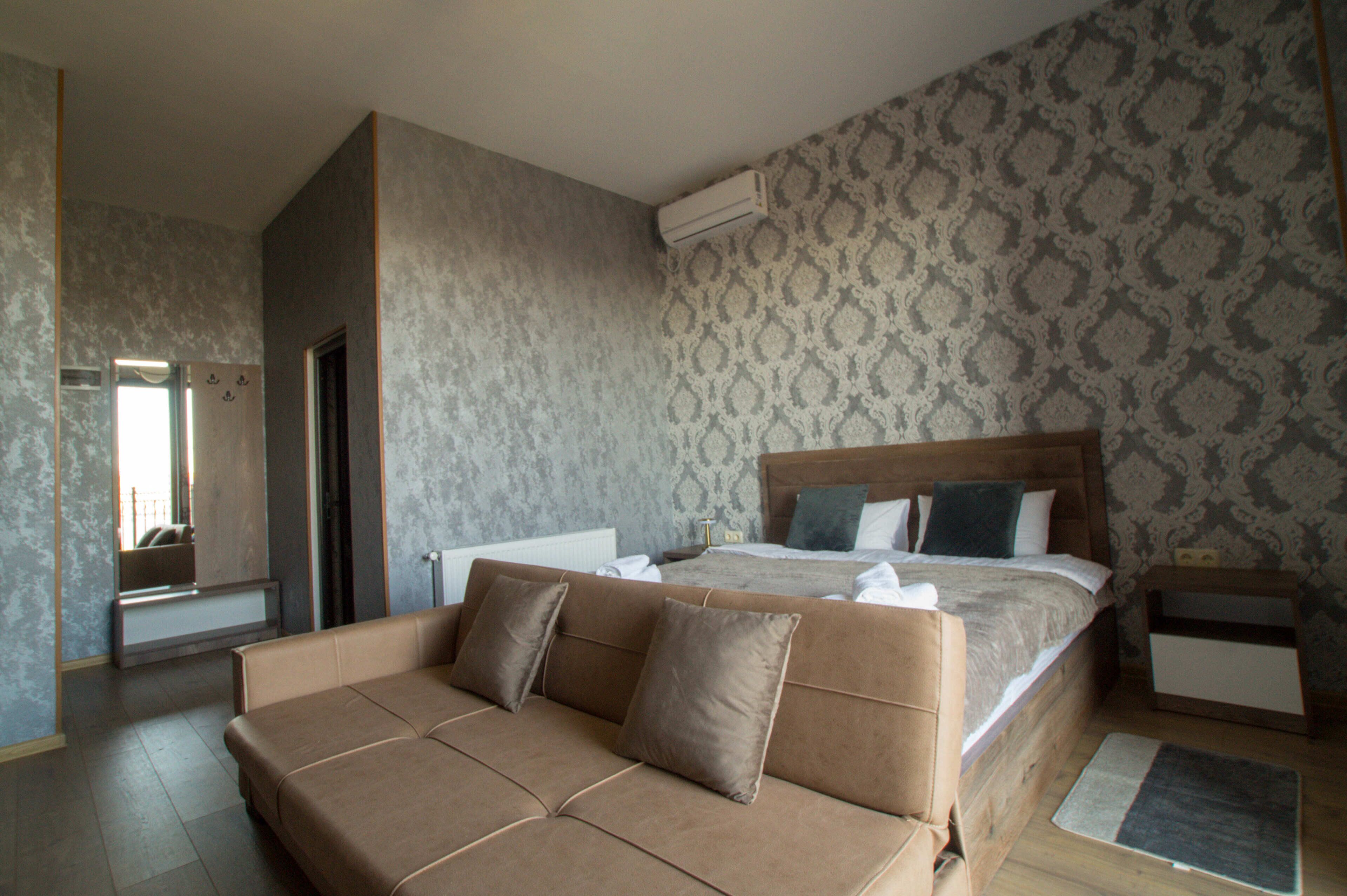 Habitación de hotel moderna con una cama grande, un sofá, un espejo y una pared con diseño.