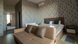 A modern hotel room with a large bed, a sofa, a mirror, and a patterned wall. - Prestige Guest House (Kutaisi)