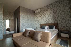 Habitació d'hotel moderna amb un llit gran, un sofà, un mirall i una paret amb un disseny decoratiu.