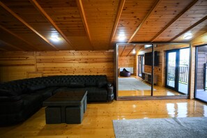 A wooden interior with a black leather sofa, a small coffee table, and a glass door leading outside. - Prestige Guest House (Kutaisi)