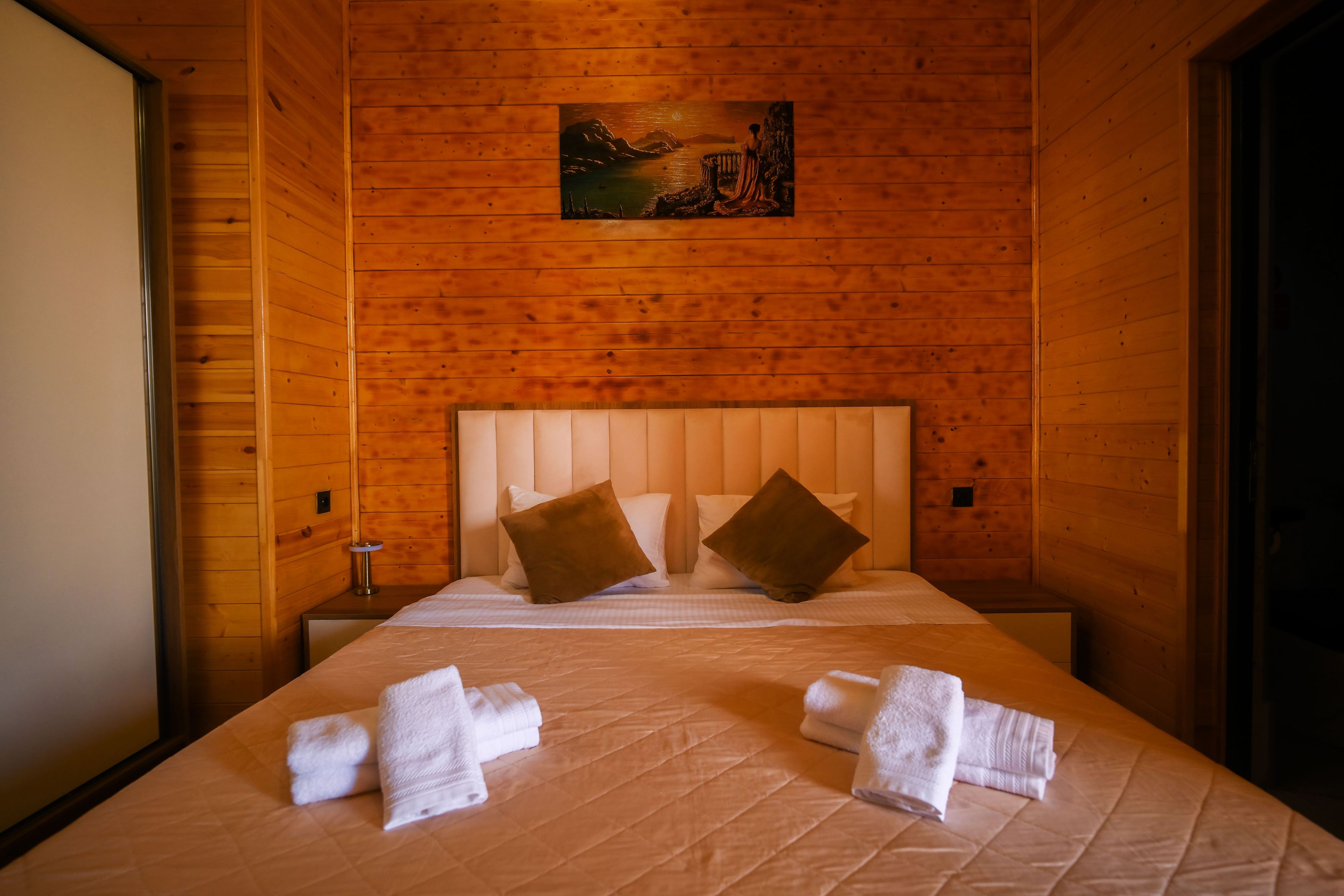 Une pièce en bois avec un lit, des oreillers et des serviettes.
