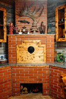 Una chimenea con revestimiento de ladrillo, una repisa de madera y varios objetos decorativos, incluyendo un cuerno de ciervo, figuritas y un reloj.