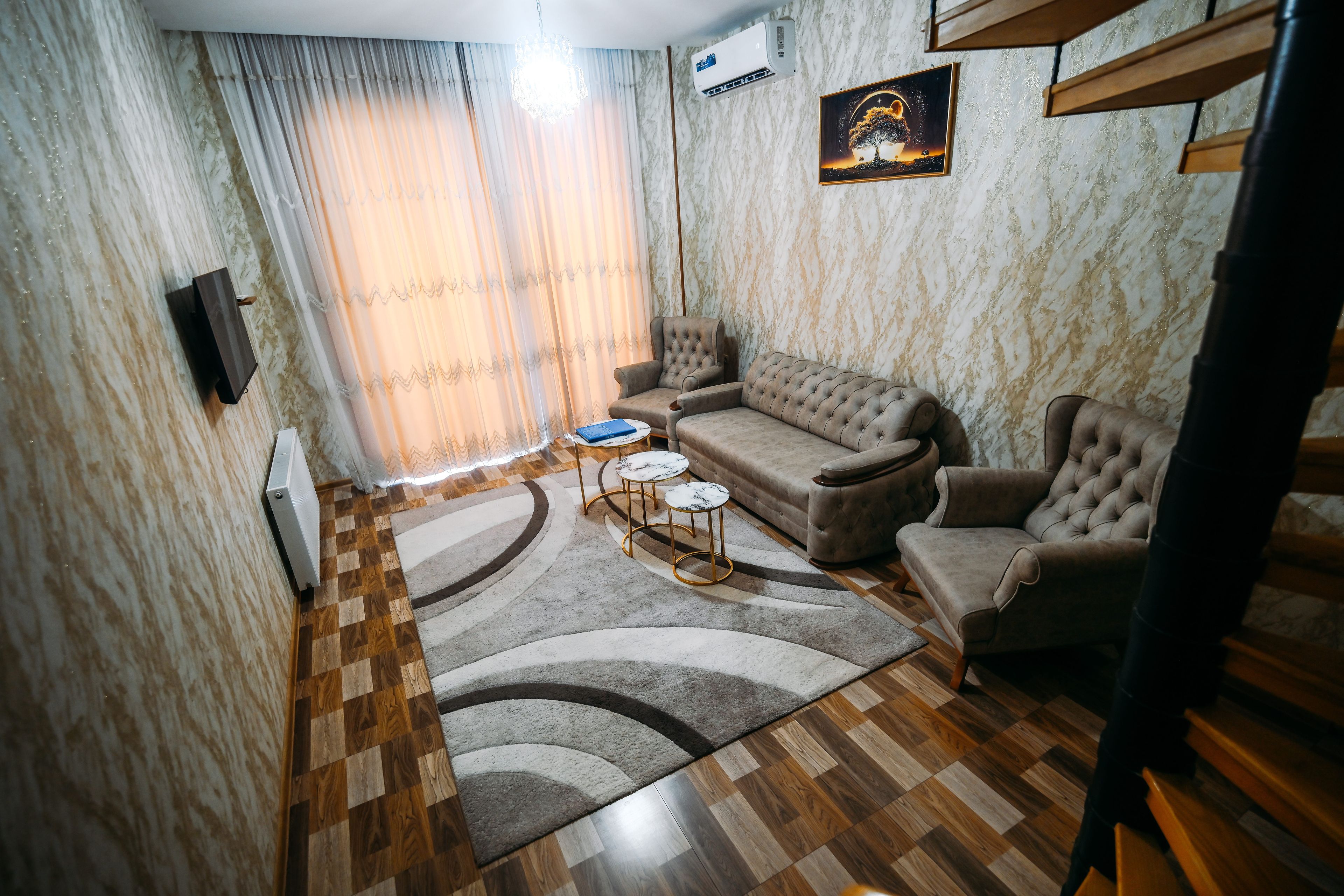 Een woonkamer met een bank, fauteuils, een salontafel en een vloerkleed.