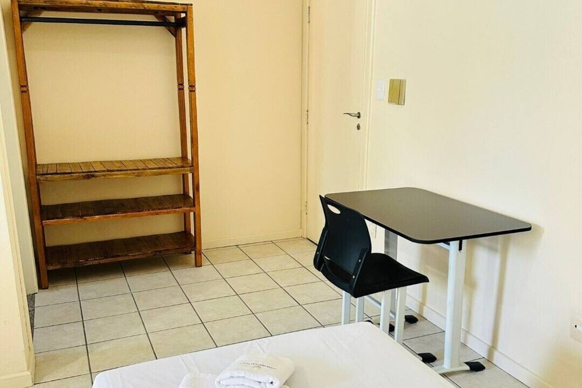 A small, clean room with a bed, a desk, and a wardrobe.