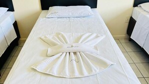Una cama individual con una colcha blanca, una toalla decorativa y un cabecero negro.