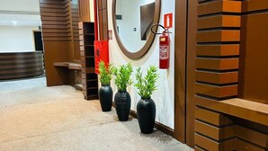 Un área de recepción de diseño moderno, con un espejo grande, un extintor y plantas en macetas.
