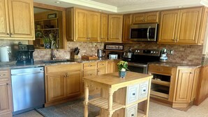 A kitchen with wooden cabinets, a stainless steel dishwasher, a microwave, and a wooden island with drawers.