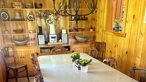 A wooden-paneled dining room with a large table, chairs, and a chandelier.