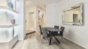 A modern dining area with a round table, black chairs, and a large mirror on the wall.
