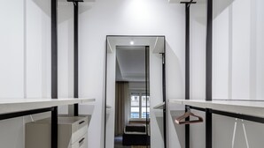 A modern, minimalist walk-in closet with a mirrored wardrobe, a hanging rack, and a desk with drawers.