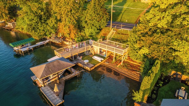 Une propriété au bord du lac, dotée d’un quai, d’un espace salon couvert et d’un escalier menant à une terrasse.