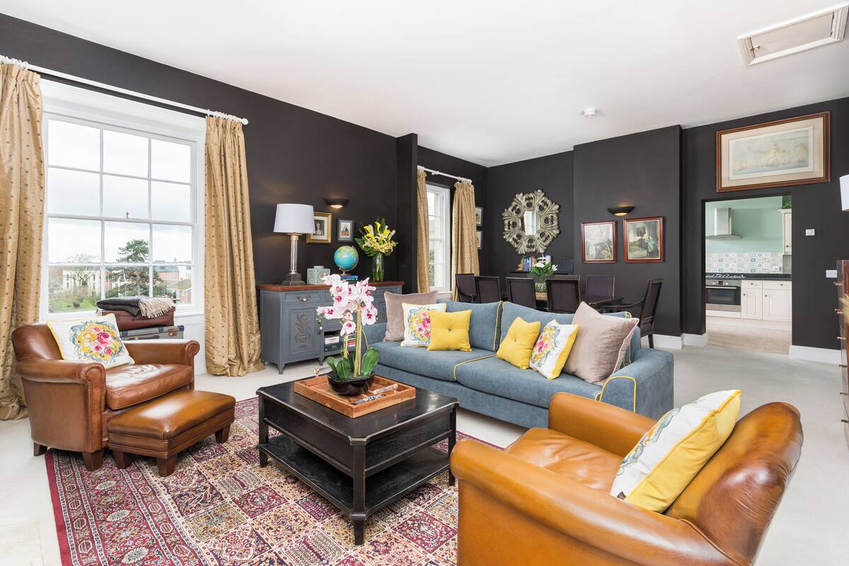 A living room with a sofa, armchairs, a coffee table, and a rug.