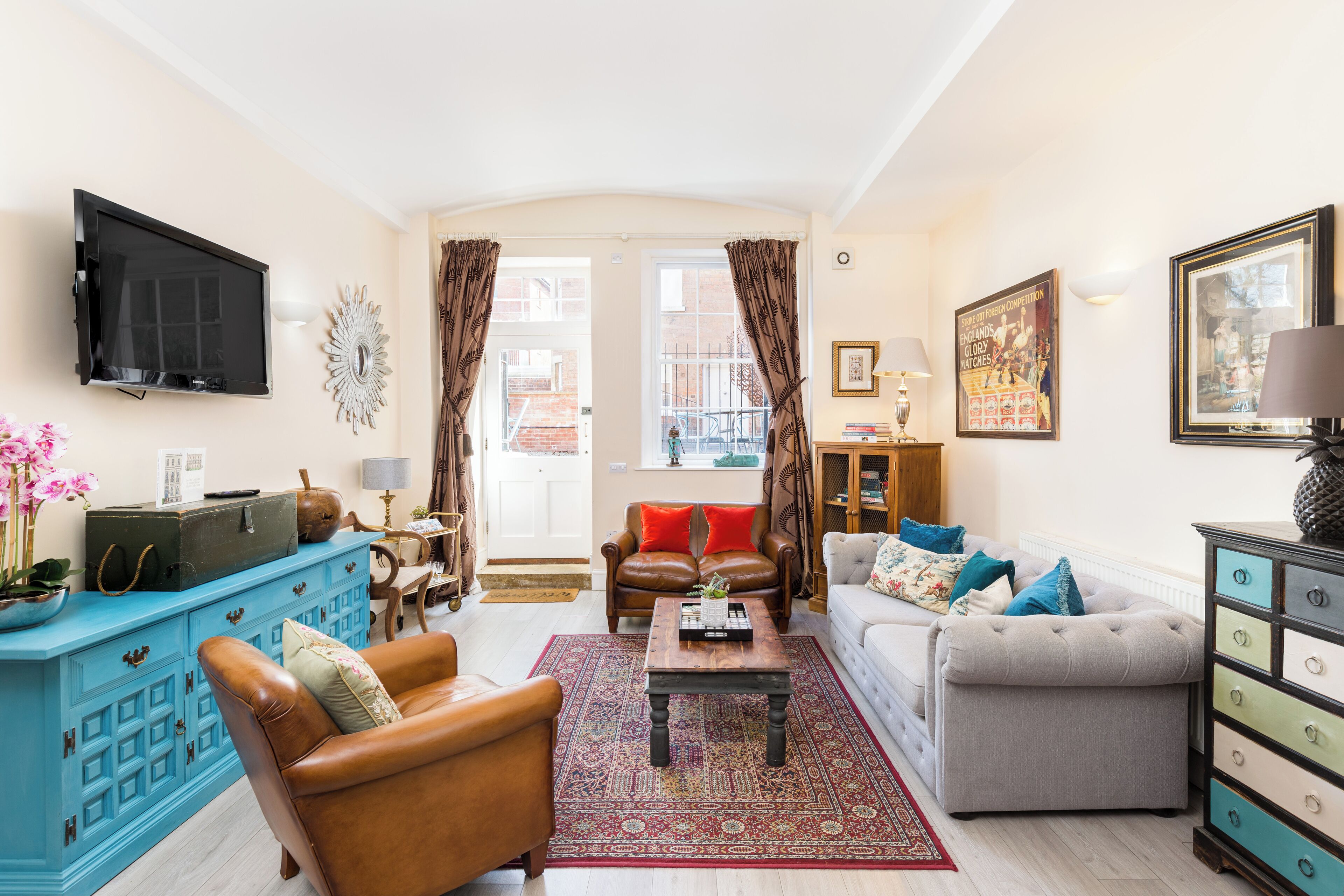 A living room with a blue cabinet, a brown leather armchair, a grey sofa, and a coffee table.