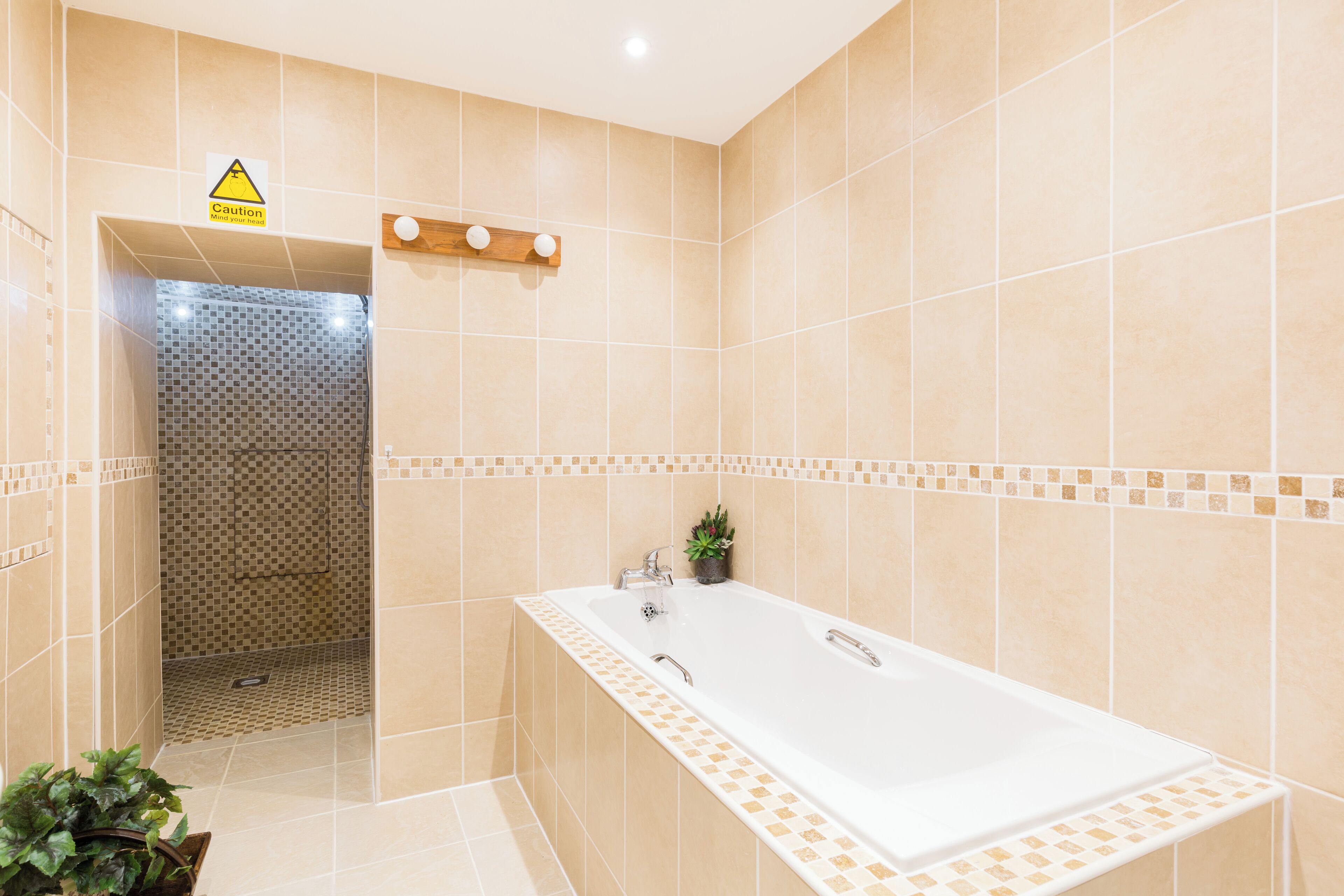 Un baño moderno con una bañera grande, una zona de ducha y un letrero de precaución.