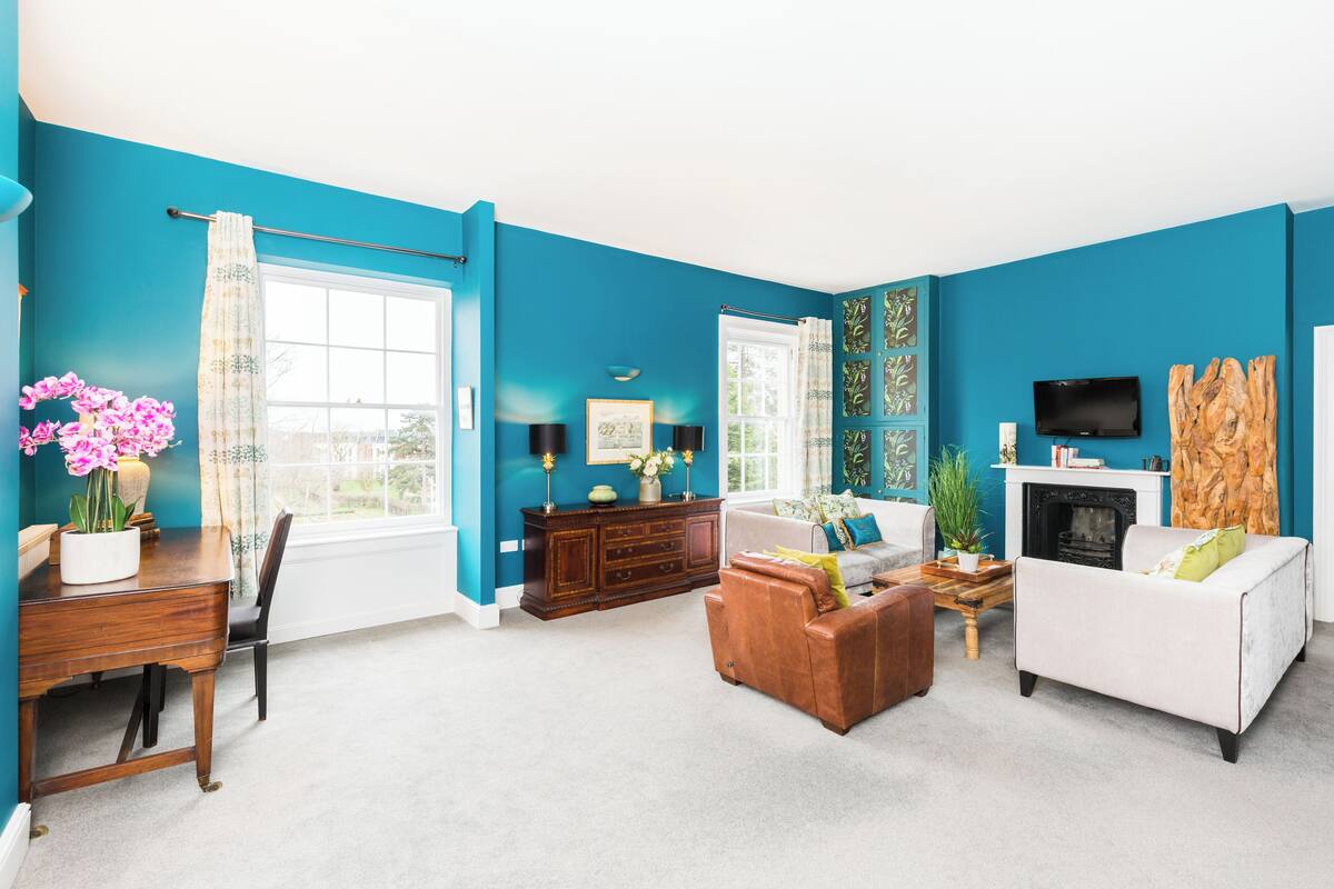 A living room with teal walls, a fireplace, a TV, and a sofa.