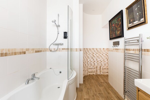 Un baño moderno con bañera, ducha y suelo de baldosas.