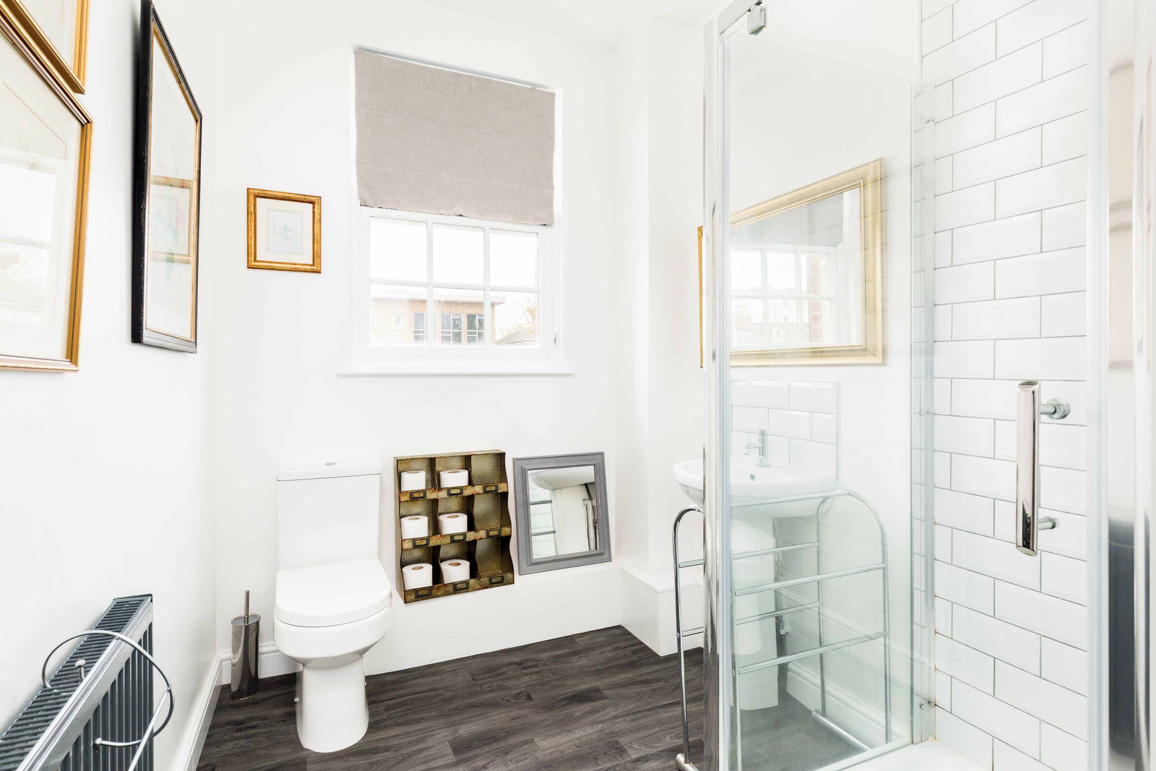 A modern bathroom with a toilet, a glass shower enclosure, and a toilet paper holder with multiple rolls.