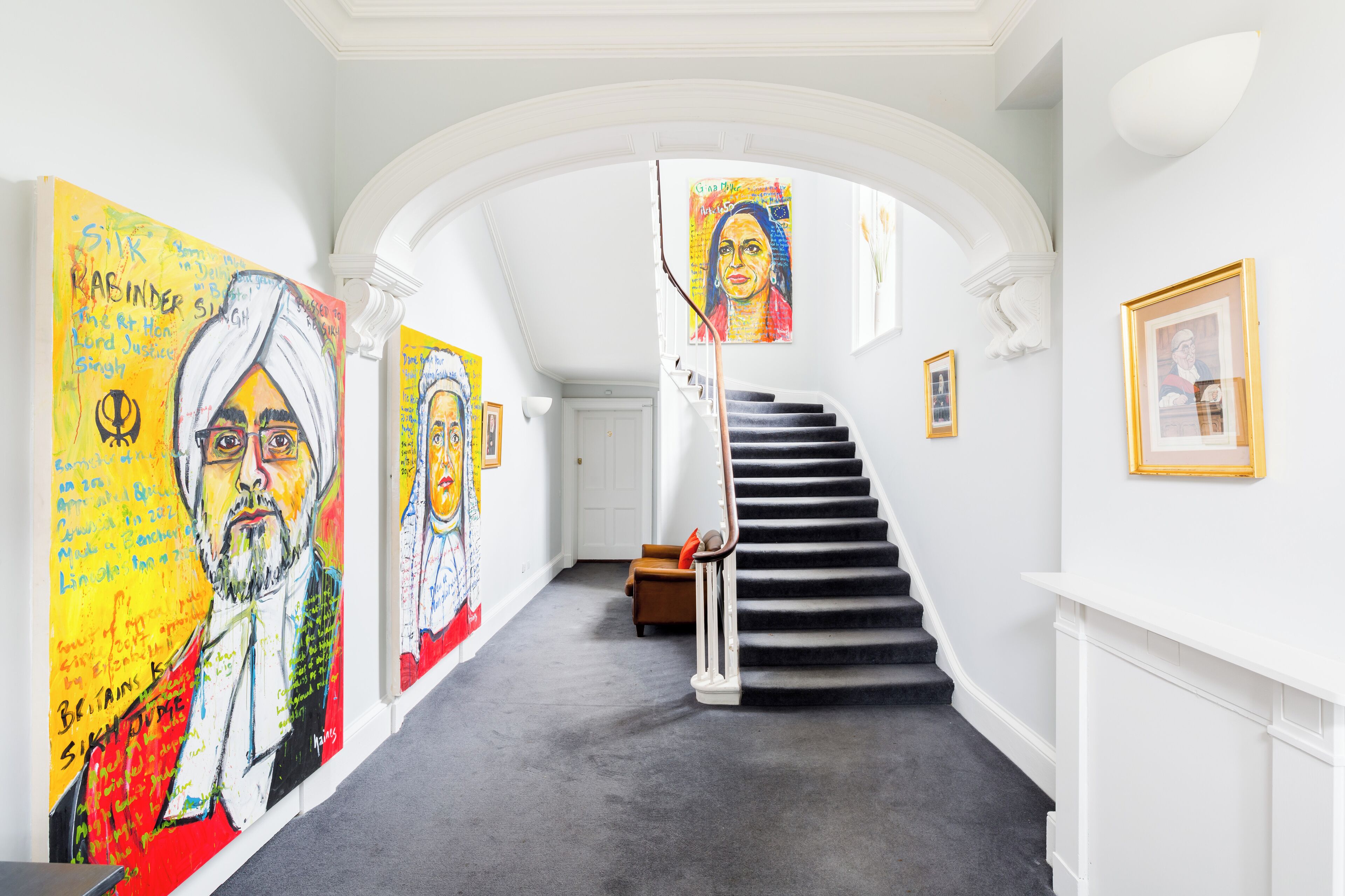 Ein Flur mit Treppe, weißen Wänden und Kunstwerken.