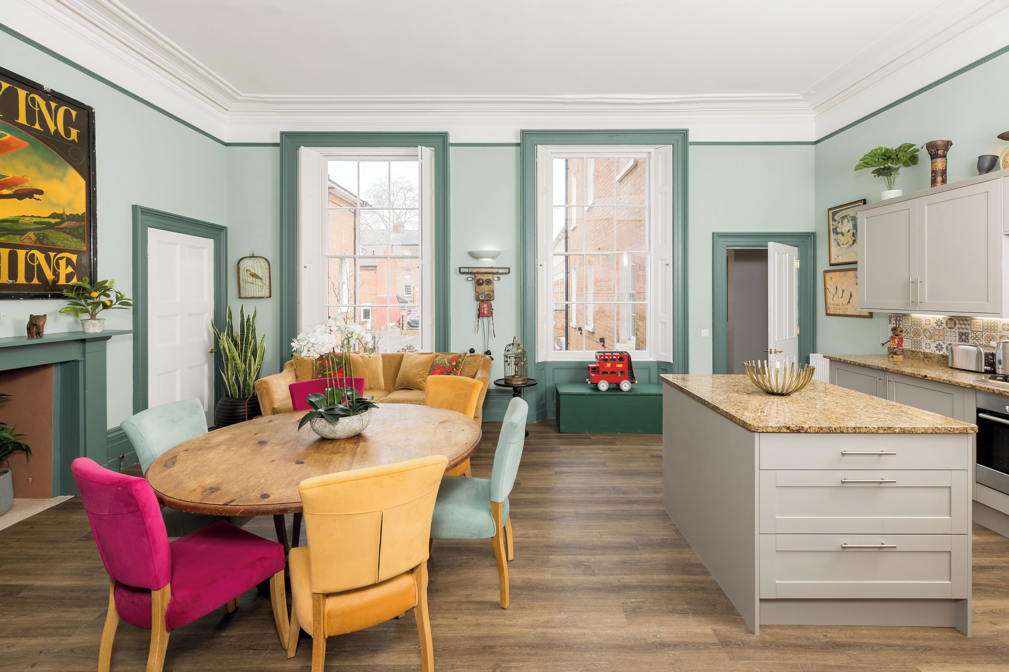 A dining area with a wooden table and chairs, a sofa, and a kitchen island with a countertop.