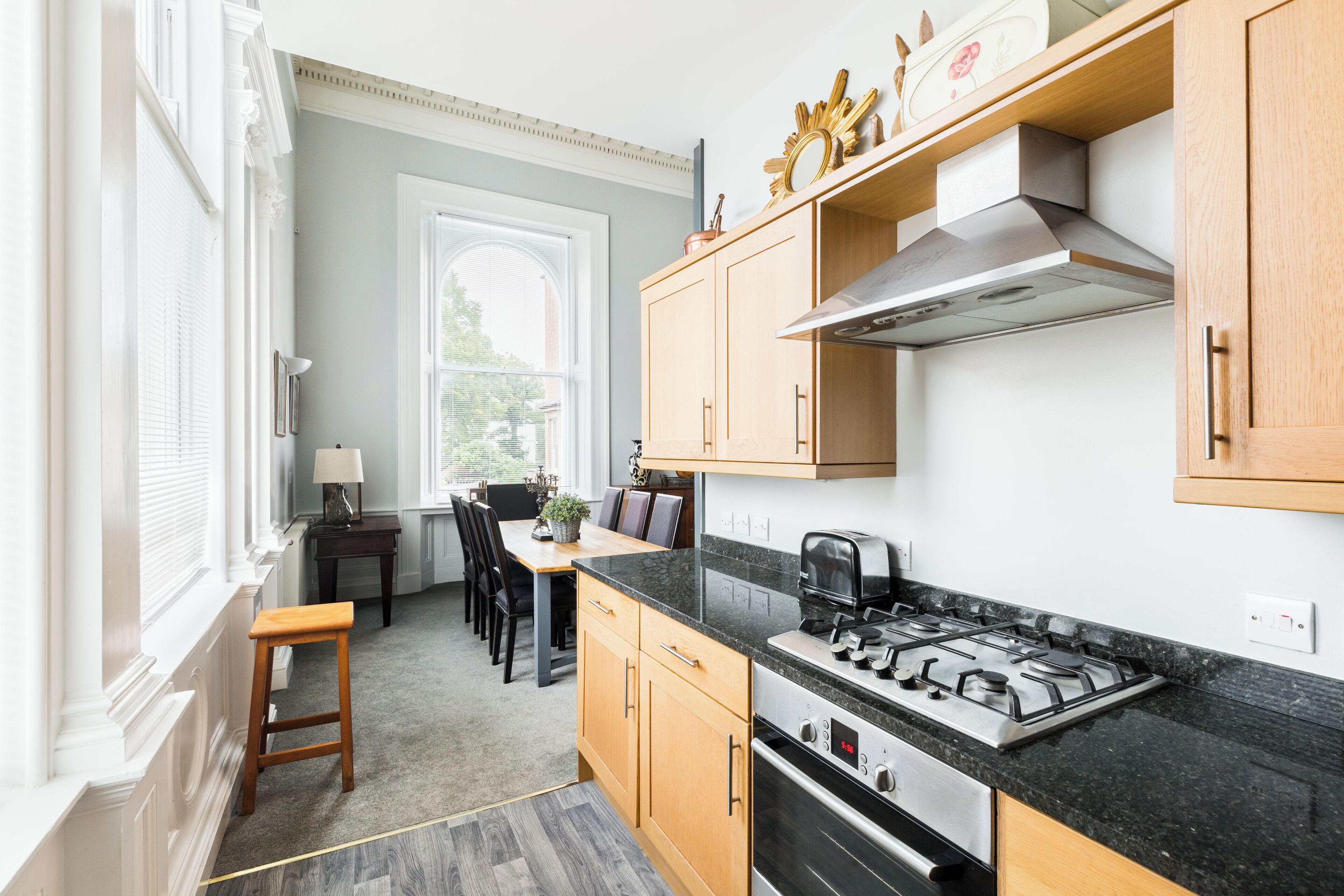 A modern kitchen with wooden cabinets, a gas stove, and a dining area with a table and chairs.