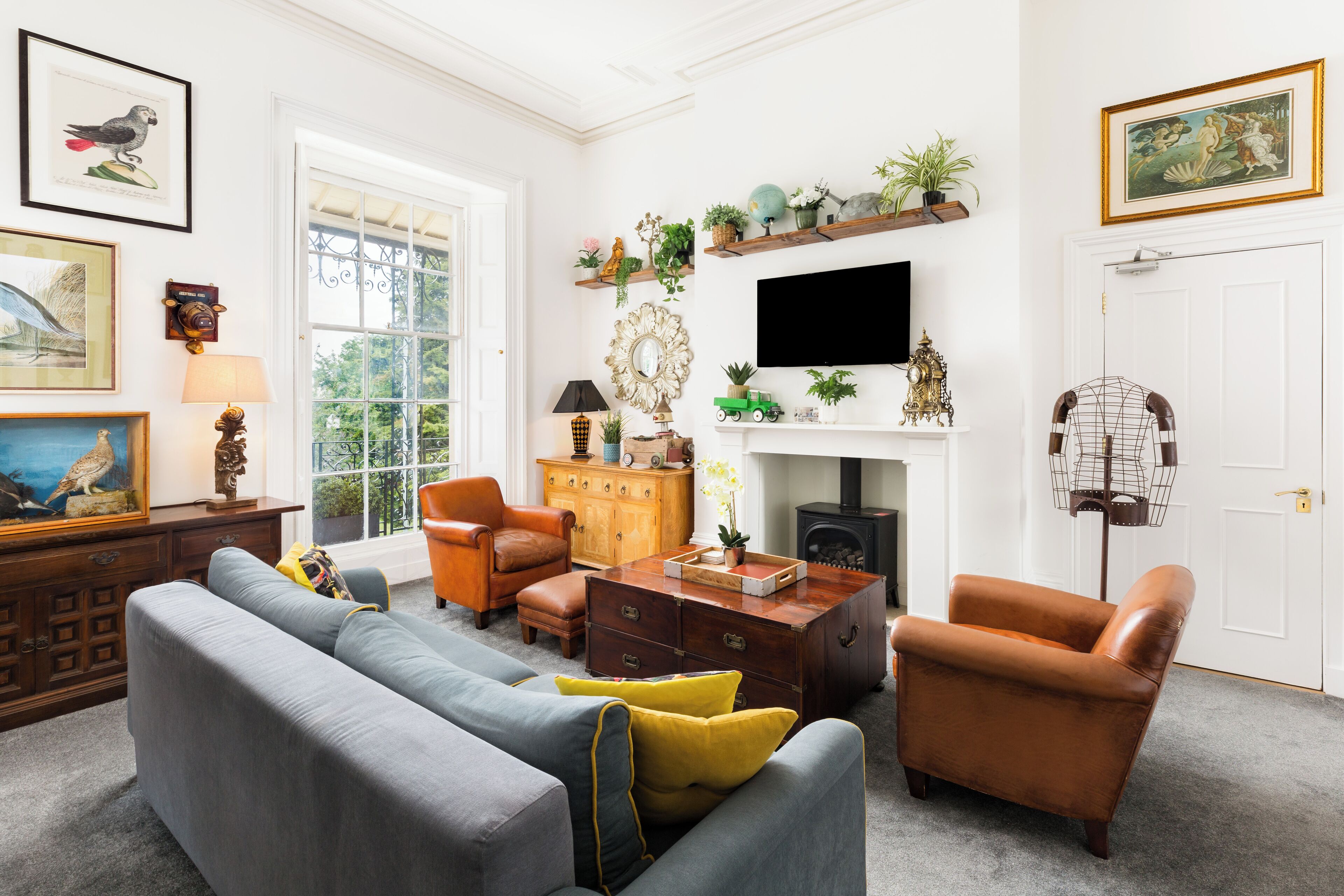 A living room with a grey sofa, brown armchairs, a wooden coffee table, and a fireplace.