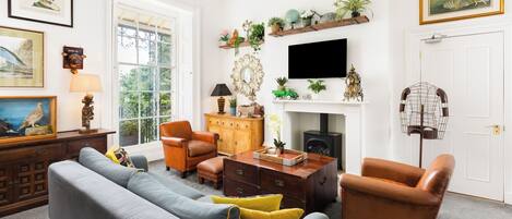 A living room with a grey sofa, brown armchairs, a wooden coffee table, and a fireplace.