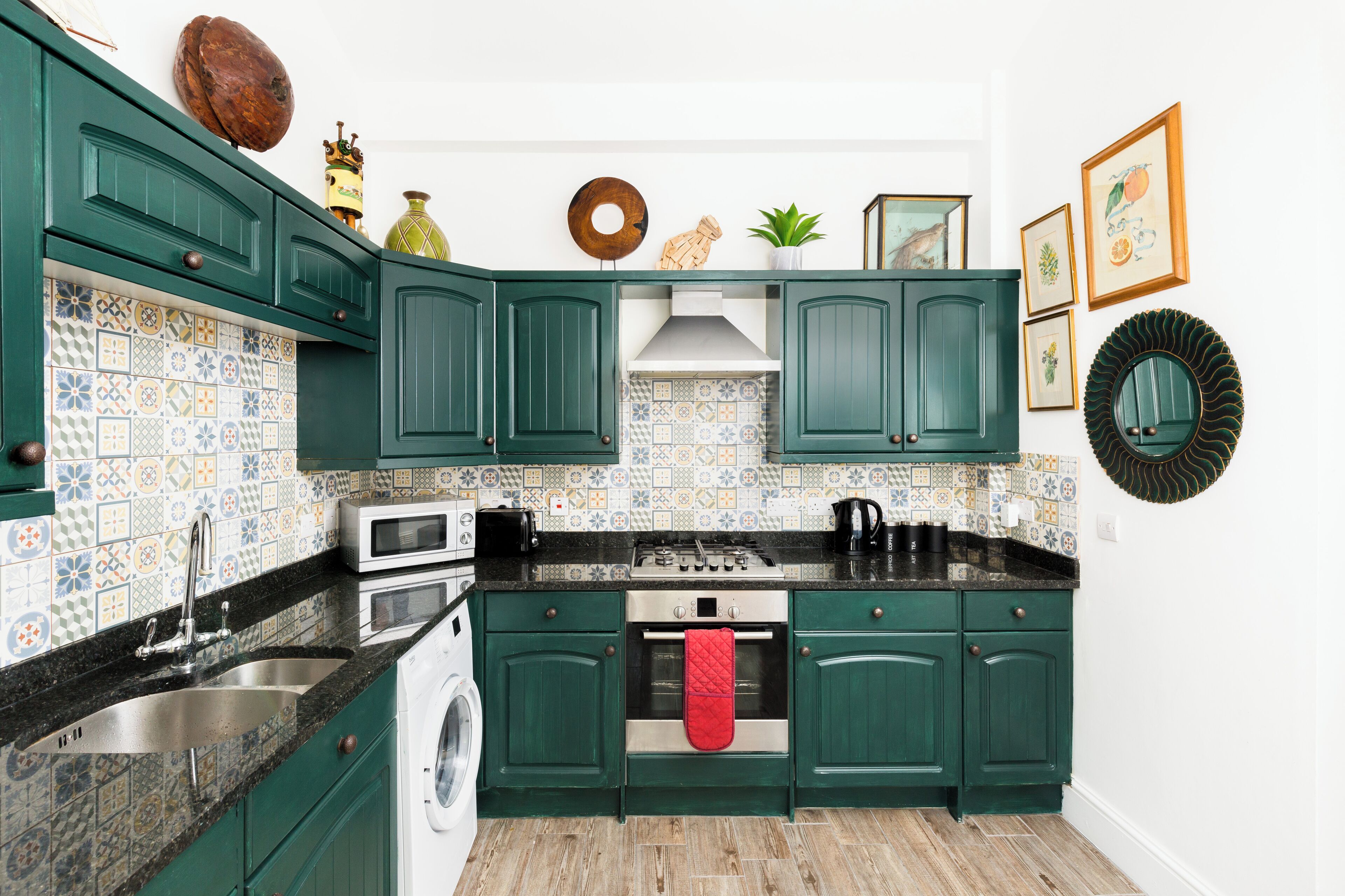 A kitchen with green cabinets, a washing machine, a stove, and a sink.