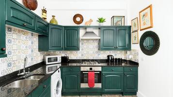 A kitchen with green cabinets, a washing machine, a stove, and a sink.