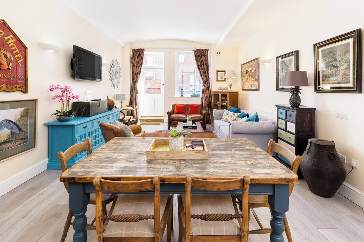 A dining area with a wooden table and chairs, a blue cabinet, and a large vase.