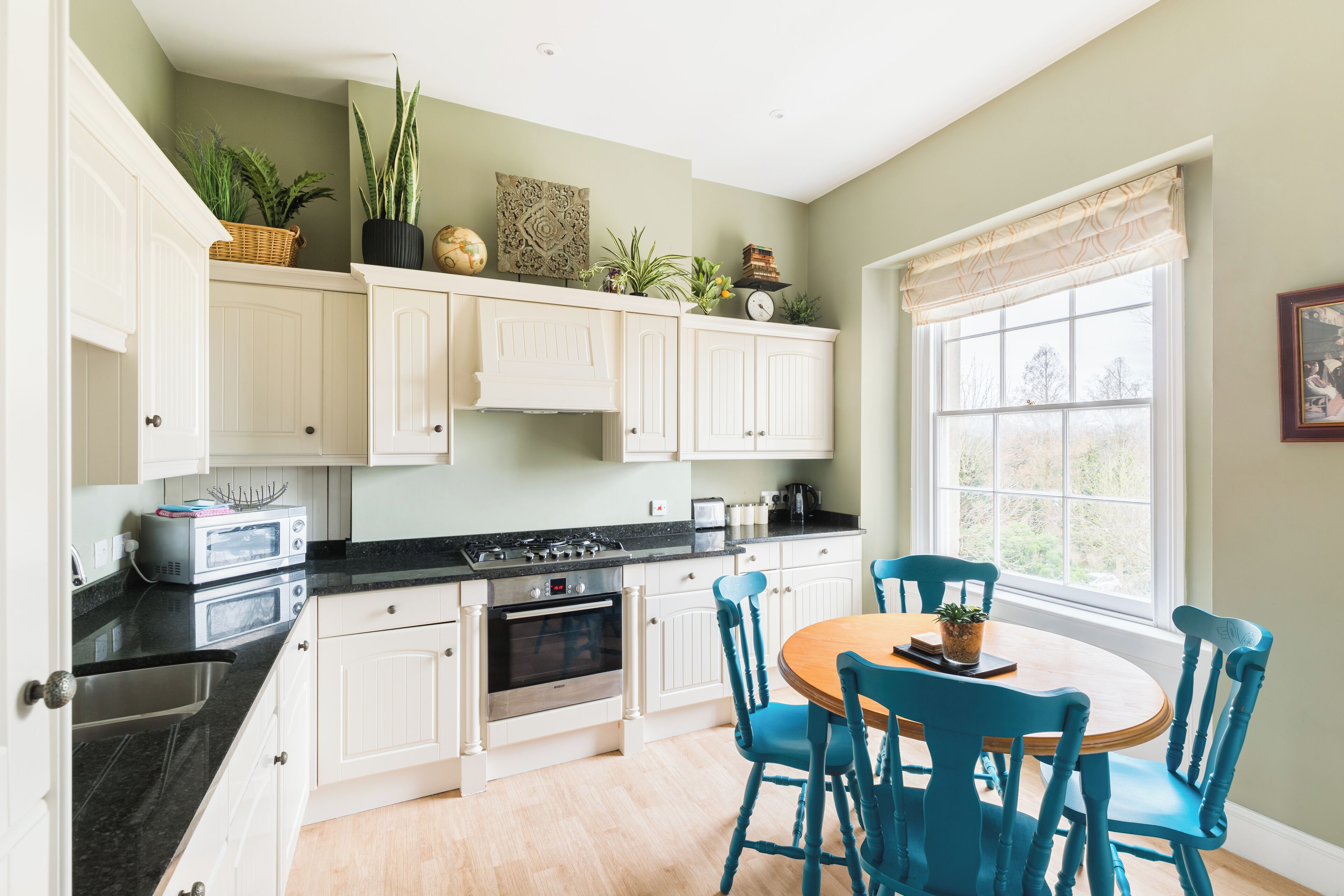 A kitchen with white cabinets, a stove, and a dining table with blue chairs.