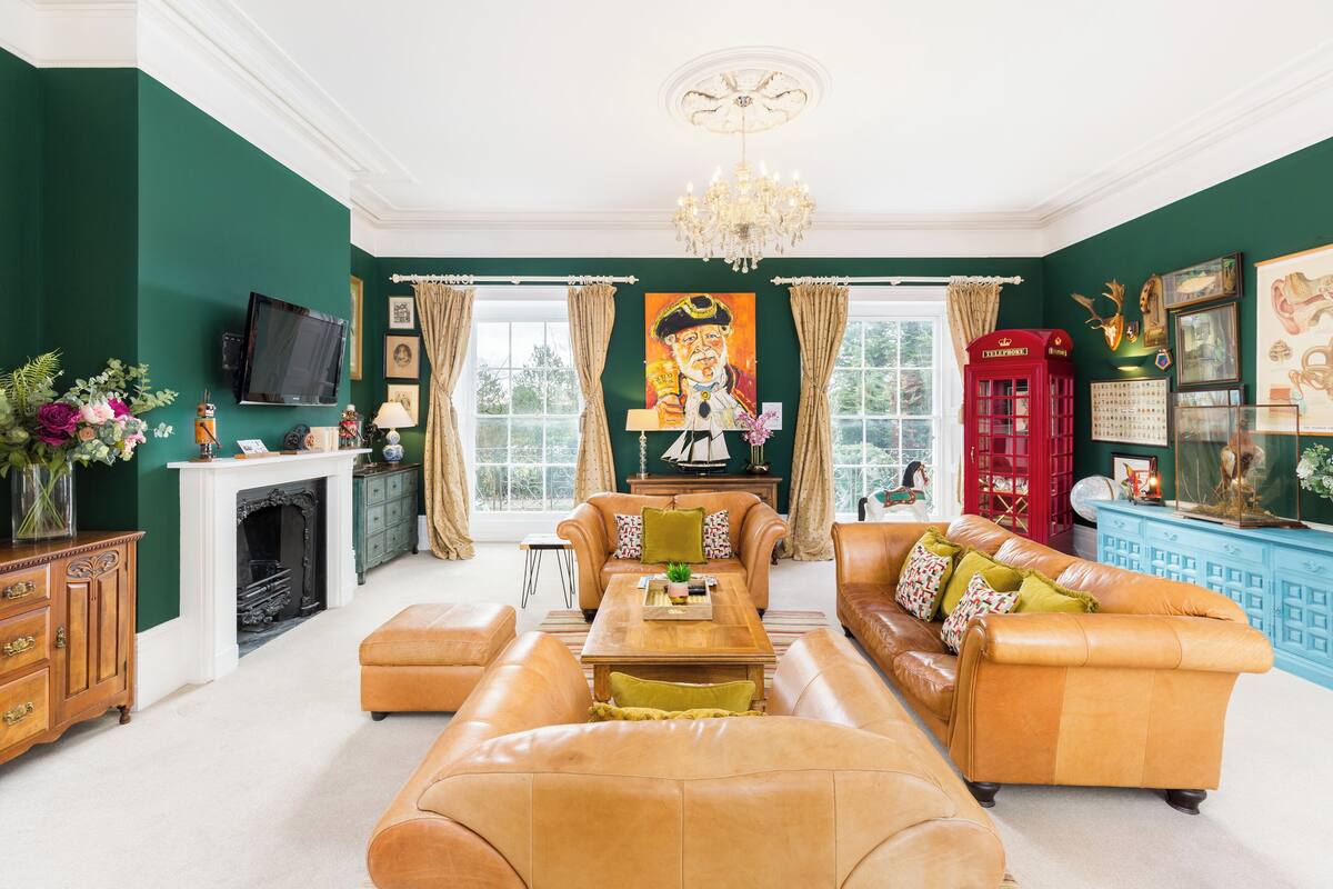 A spacious living room with a fireplace, leather sofas, a television, and a red telephone booth.