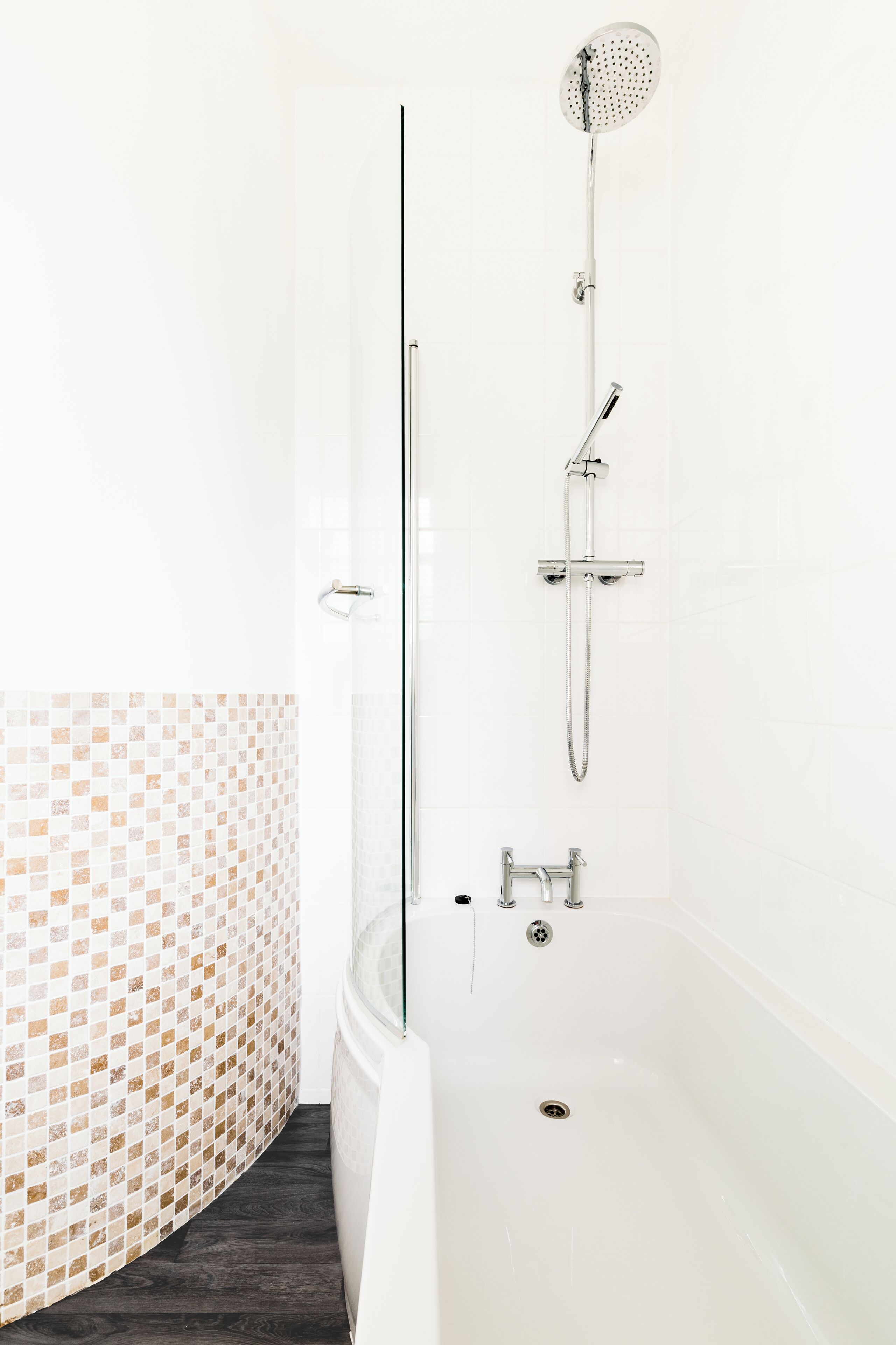 A modern bathroom with a glass-enclosed shower, a freestanding bathtub, and a mosaic tile wall.