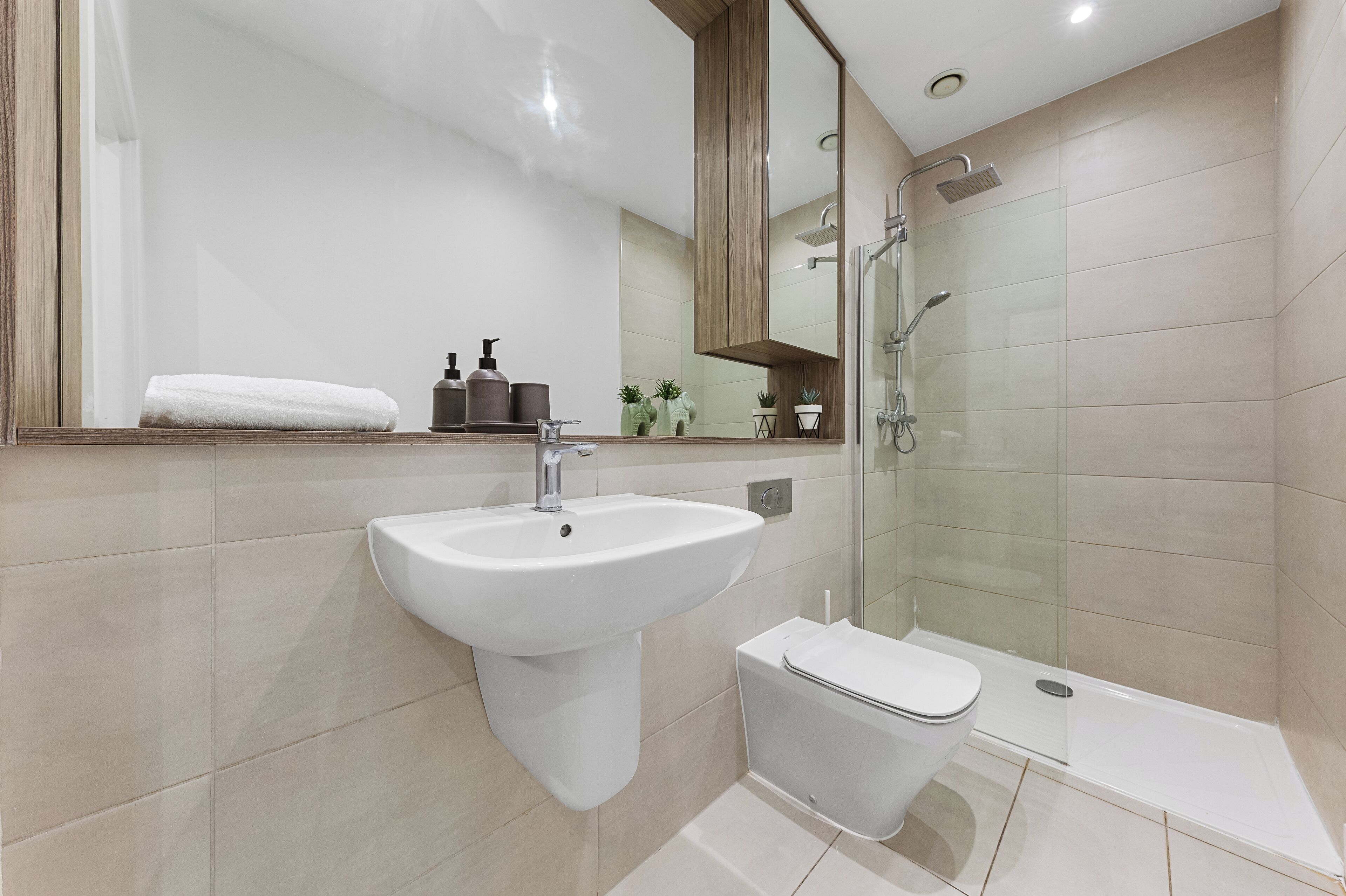 A modern bathroom with a sink, toilet, and glass-enclosed shower.
