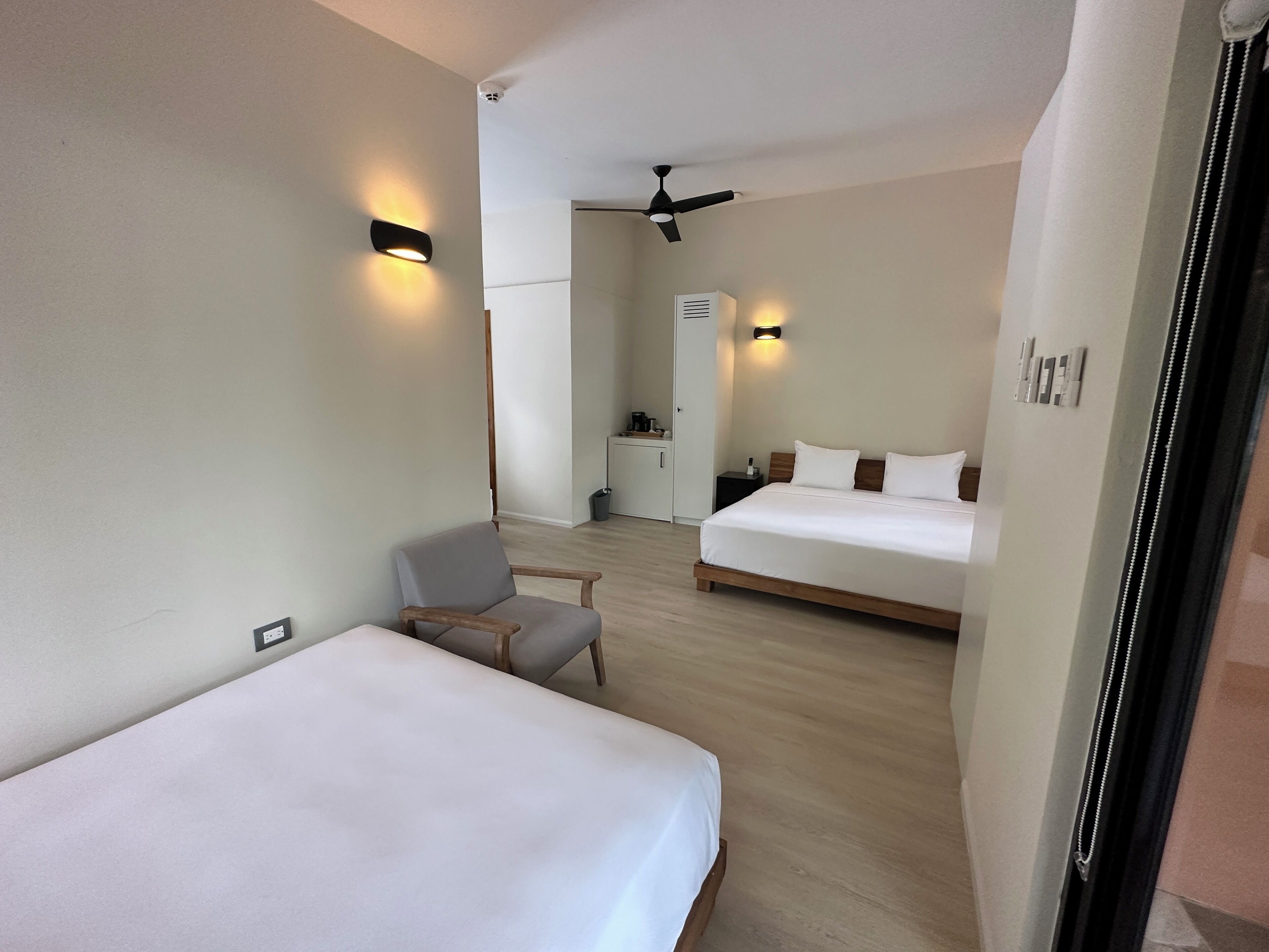 Habitación de hotel con dos camas, una silla, un escritorio y kitchenette.