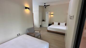 Habitación de hotel con dos camas, una silla, un escritorio y kitchenette.