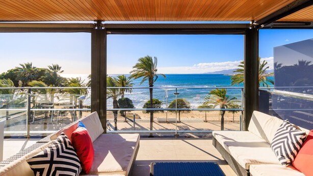 Un balcón con vistas al mar, amueblado con dos sofás y una mesa.