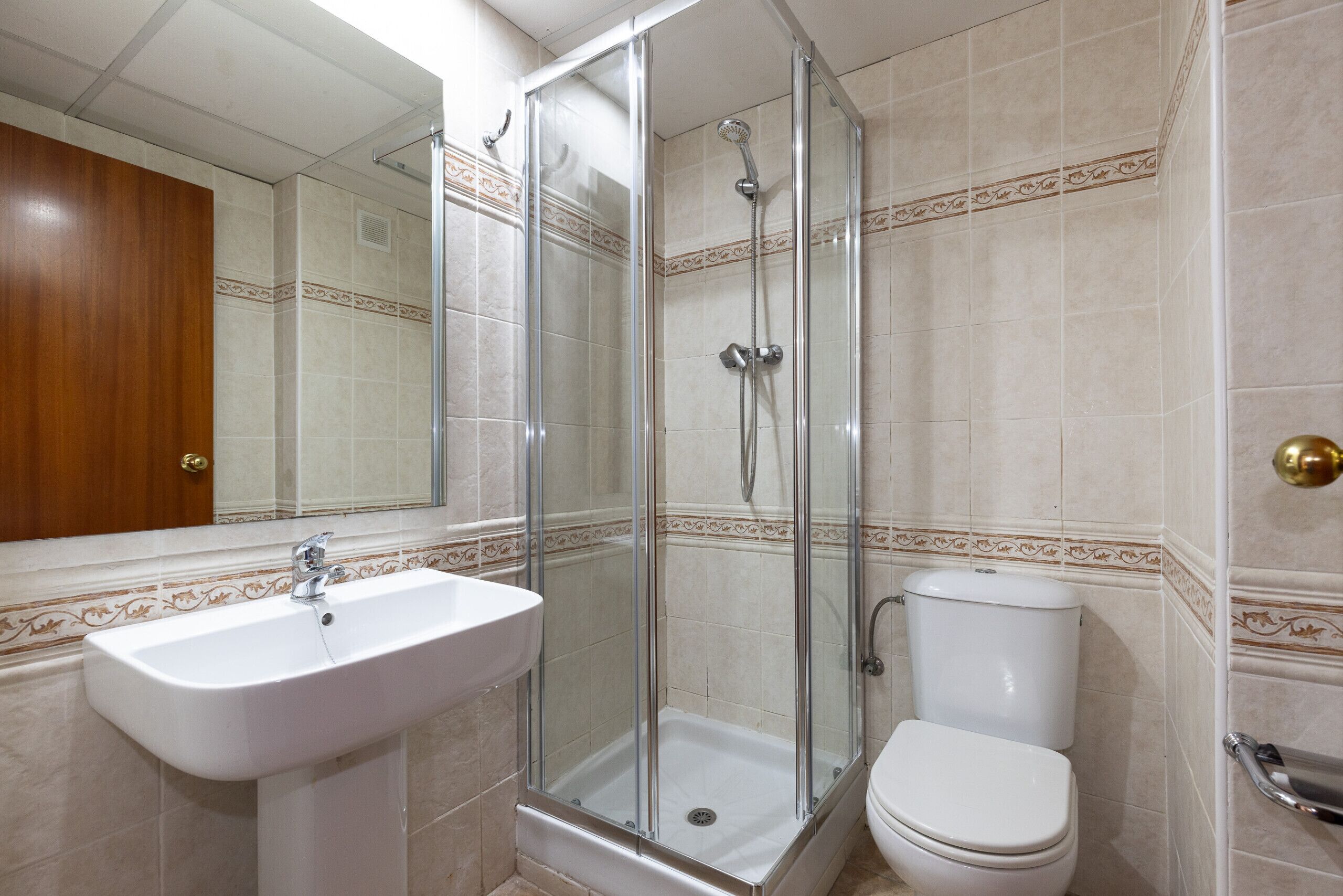 Een badkamer met een douche met glazen wand, een wit wastafelmeubel en een toilet.