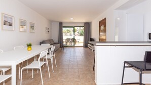 A modern kitchen with white cabinets, a black countertop, and a dining area with a white table and chairs. - Wake up to pool views · Festival Village (Salou)