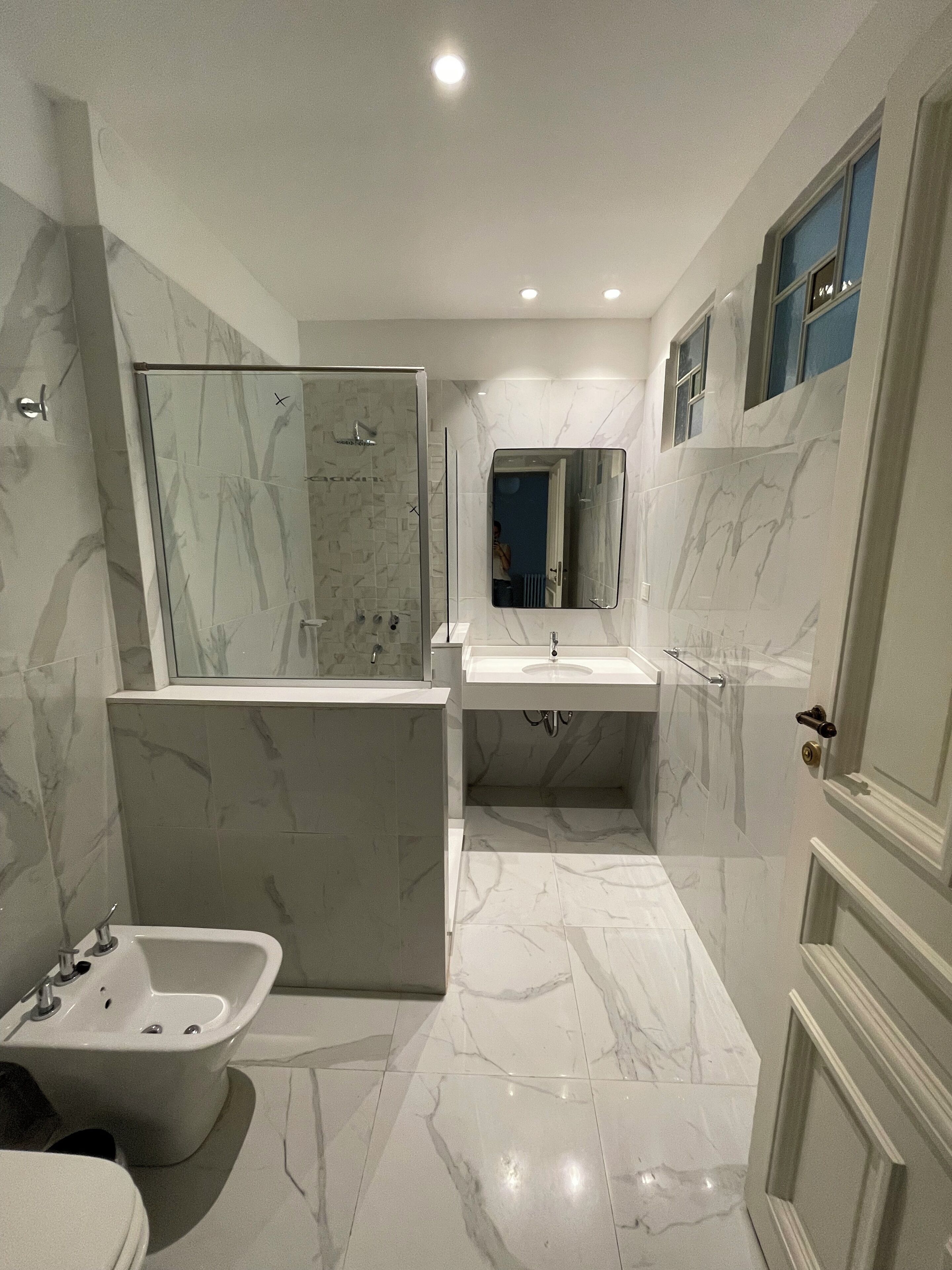 Un baño moderno con ducha de vidrio, bañera independiente y tocador con espejo.