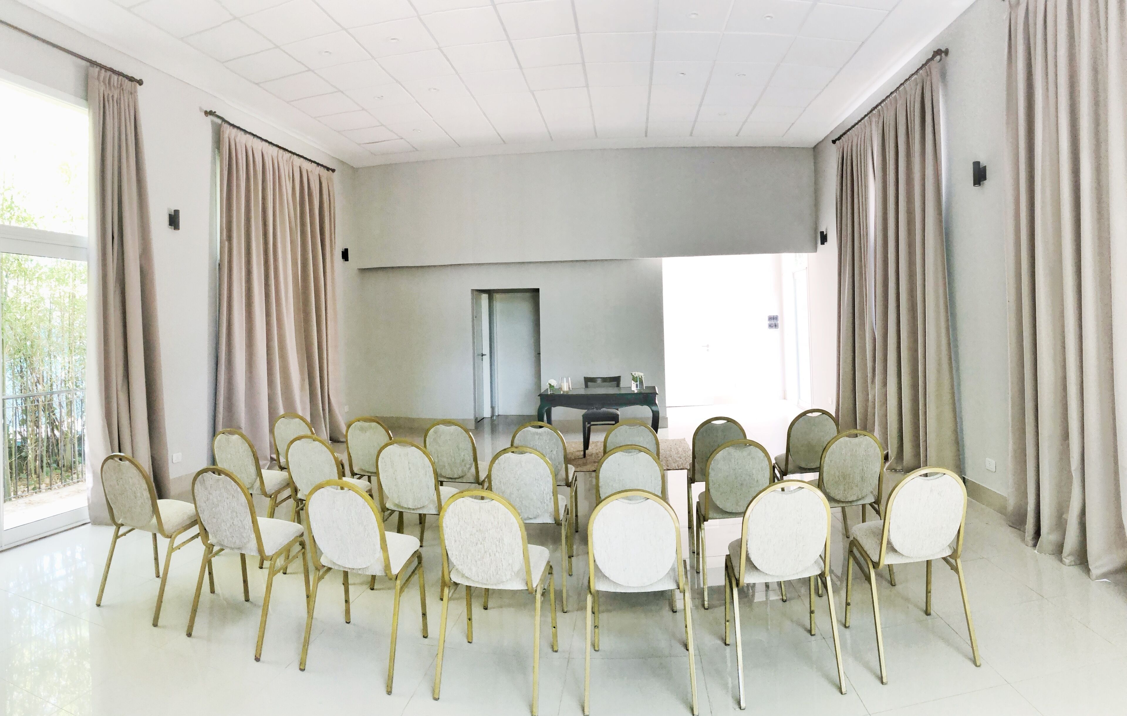 A conference room with a round table, beige curtains, and rows of chairs.