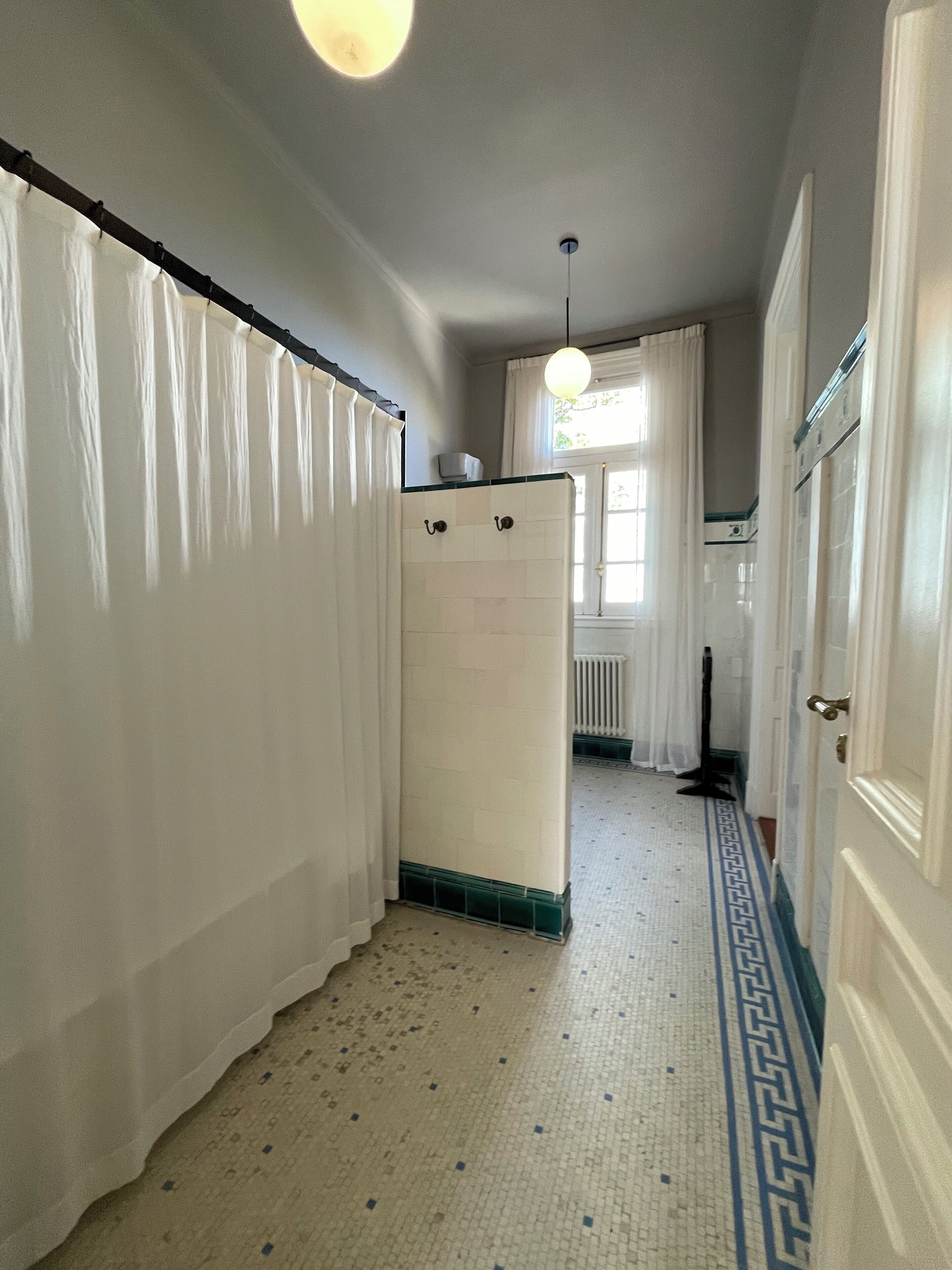 A narrow hallway with a white radiator, a white door, and a patterned floor.