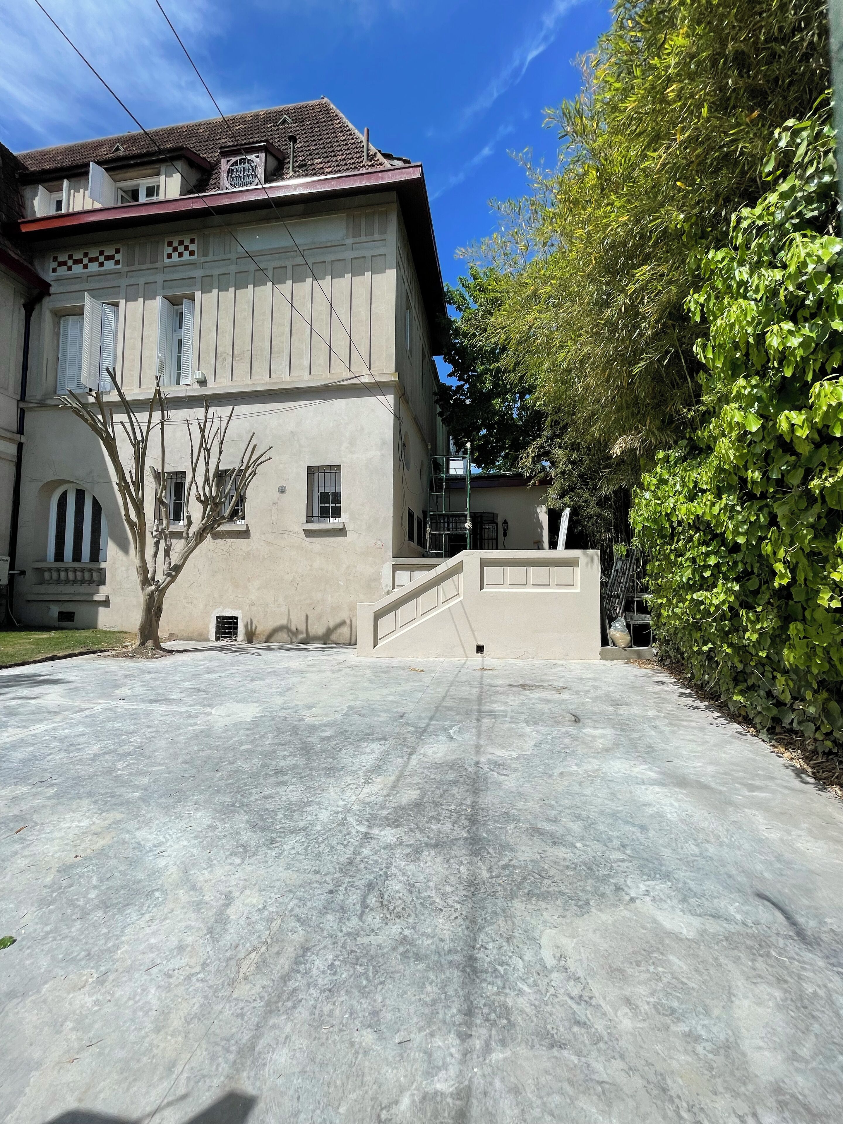 Un bâtiment à deux étages, avec une allée en béton et un escalier menant à l’entrée.